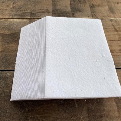Pilha de folhas de papel branco texturizado com padrão de linhas finas na lateral sobre mesa de madeira
