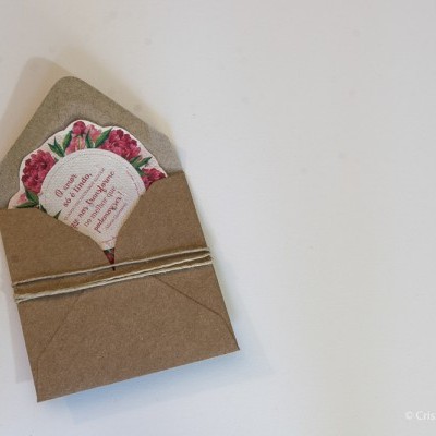 Envelope castanho com cartão floral decorativo em papel reciclado sobre fundo branco