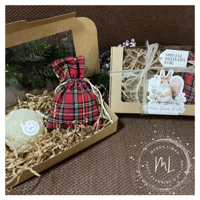 Caixa de presente em cartão reciclado com saco de tecido xadrez e sabonete creme, junto com outra embalagem decorada com etiqueta e adesivo de coelho.