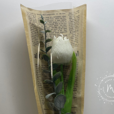 Rosa branca artificial em papel com padrão de texto, folhas verdes e fundo branco