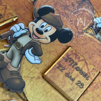 Figura do Mickey Mouse vestido de explorador com texto manuscrito ao lado num fundo castanho