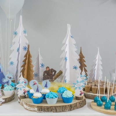 Mesa de festa com sobremesas azuis e brancas e decoração temática de Natal e castelo