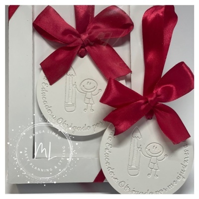 Etiqueta branca redonda com laço vermelho e gravura de lápis e boneco sorridente