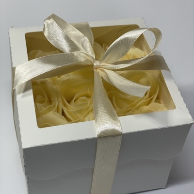 Caixa branca com flores amarelas artificiais e fita de cetim bege clara amarrada