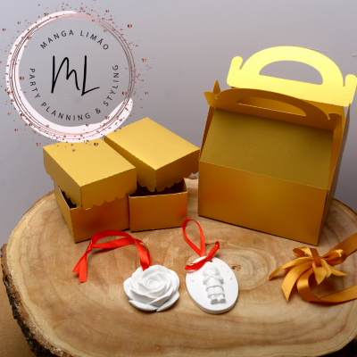 Caixas douradas para presentes, ornamentos brancos com fitas, tudo sobre base de madeira