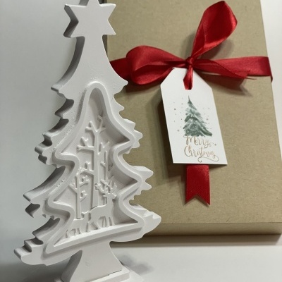 Decoração de Natal branca em forma de árvore com caixa de presente castanha e fita vermelha.