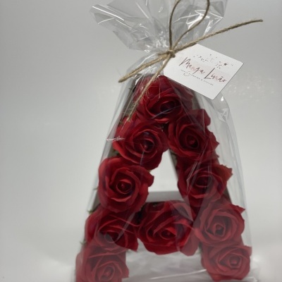 Arranjo floral vermelho em forma de letra A embalado em plástico transparente com cordel e etiqueta