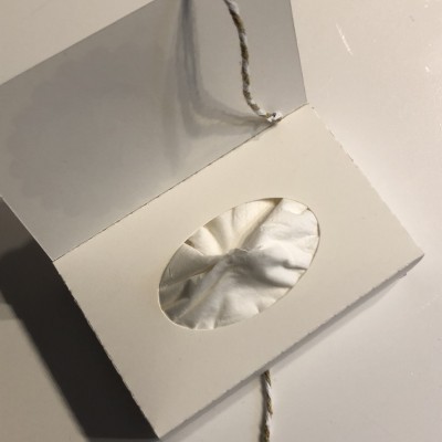 Etiqueta branca com janela oval transparente e cordão branco e dourado