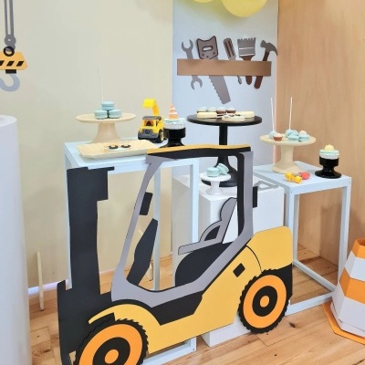 Decoração temática de construção com empilhador, bolos e macarons em suportes em mesa branca