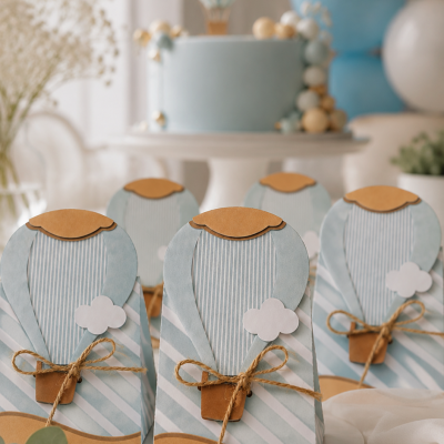 Cestas decorativas em papel azul claro com laços de corda e nuvens, em frente a bolo azul em festa