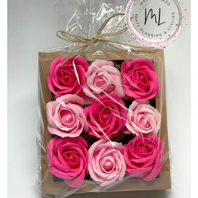 Caixa com nove rosas artificiais em tons de rosa embaladas em plástico transparente