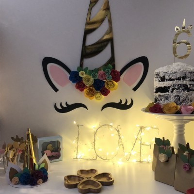 Decoração de festa de unicórnio com bolo, flores coloridas e iluminação com palavra LOVE
