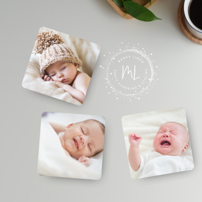 Ímanes com fotos de bebés numa superfície branca, caneca de café e folha verde ao fundo