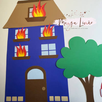 Casa azul de papel com fogo nas janelas e árvore verde ao lado