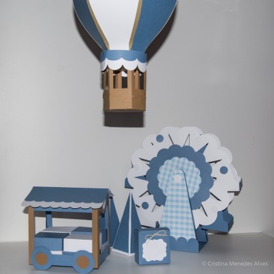 Brinquedos de papel e cartão em azul, branco e castanho com balão de ar quente, roda gigante e carrinho.