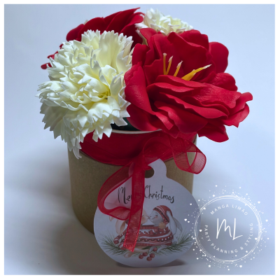 Arranjo floral natalício em caixa castanha com laço vermelho e etiqueta 'Merry Christmas'