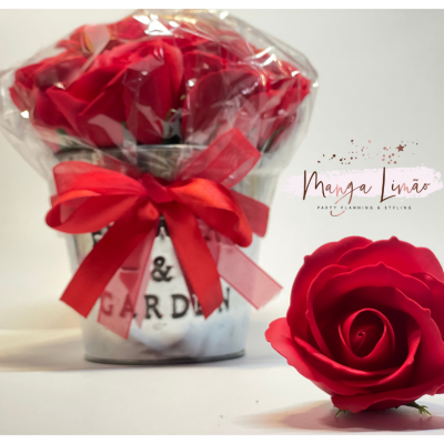 Vaso branco com rosas vermelhas artificiais e laço vermelho, uma rosa vermelha solta ao lado, fundo branco