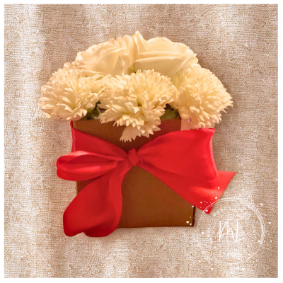 Caixa de presente com laço vermelho e flores brancas artificiais