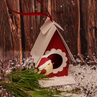 Casa de pássaros decorativa vermelha e branca com laço vermelho e raminhos de pinheiro