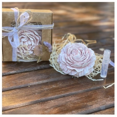 Flor decorativa rosa clara com embalagem de vidro e caixa de papel kraft sobre mesa de madeira