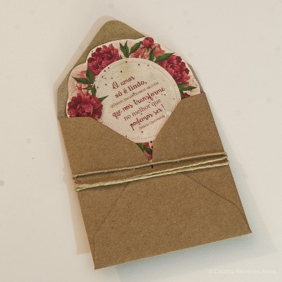 Envelope castanho com cordão e cartão floral com texto em português