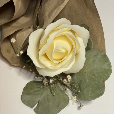 Ramo com flor artificial creme e folhas verdes em papel castanho