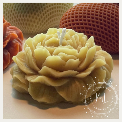 Vela decorativa em forma de flor amarela clara sobre superfície clara com velas texturizadas ao fundo