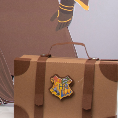 Mala castanha com emblema colorido 'HP' em fundo cinzento