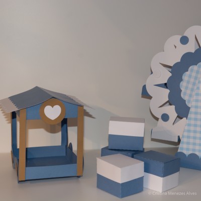 Estrutura de papel azul e castanho com coração branco, caixas azul e branco e decoração branca e azul xadrez