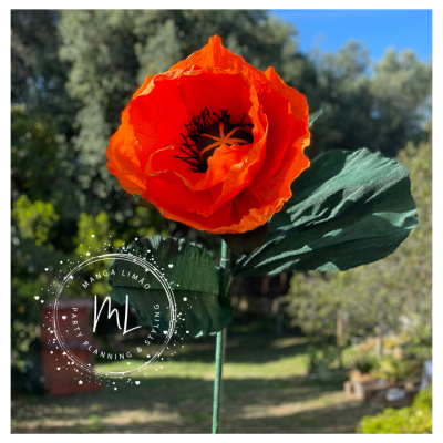 Flor artificial vermelha com folhas verdes num ambiente exterior