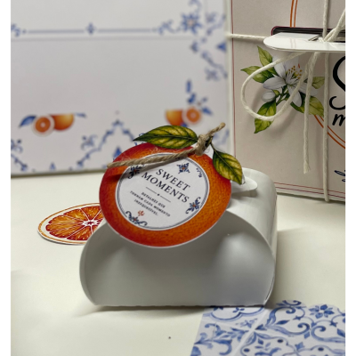 Caixa branca com etiqueta em forma de laranja e texto SWEET MOMENTS com folhas verdes