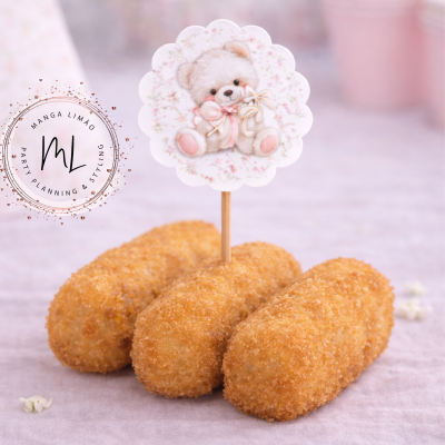 Três croquetes empanados dourados com decoração de papel floral e urso de pelúcia