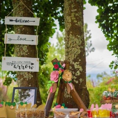 Placas decorativas penduradas numa árvore com textos em inglês e decoração de festa exterior