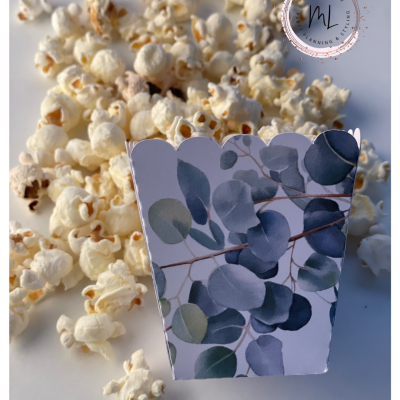 Pipocas com caixa decorada por padrão de folhas em fundo branco