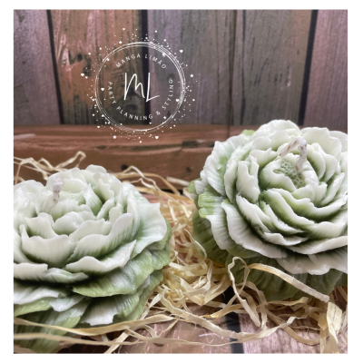 Velas em forma de flores verdes e brancas numa caixa de madeira com palha.