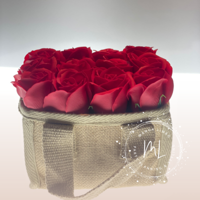 Caixa bege de tecido com alça contendo doze rosas vermelhas