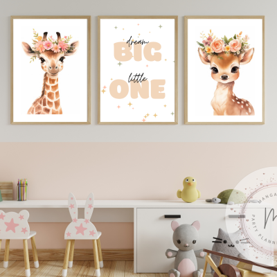 Três quadros infantis com girafa, texto motivacional e cervo numa parede acima de mesa e cadeiras pequenas em ambiente infantil.