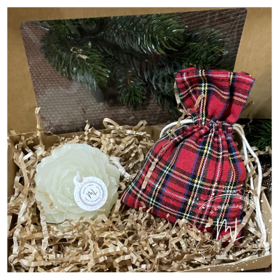 Conjunto com vela em forma de flor e saco xadrez vermelho numa caixa com enchimento