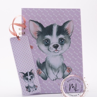 Caderno lilás com padrão de ossos e desenho de cão e marcador de páginas com fita cor de rosa