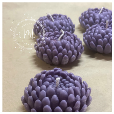 Velas roxas em formato de flor com pétalas grossas sobre superfície bege