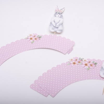 Chapéus de papel cor-de-rosa com pontos brancos e flores decorativas, com suporte de coelho em fundo branco.