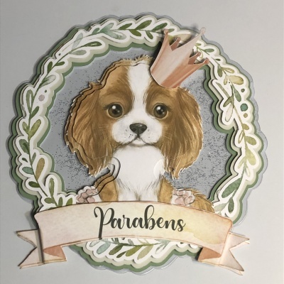 Cartão decorativo de um cão com coroa e a palavra Parabéns