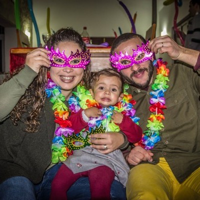 Família com colares floridos e máscaras cor de rosa brilhantes sentados no chão
