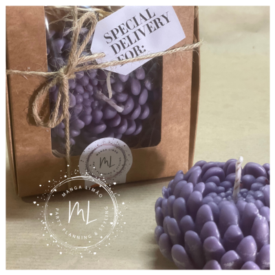 Vela roxa decorativa com textura de pétalas ao lado de caixa castanha com etiqueta SPECIAL DELIVERY