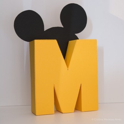 Objeto decorativo amarelo com orelhas pretas em formato de letra M