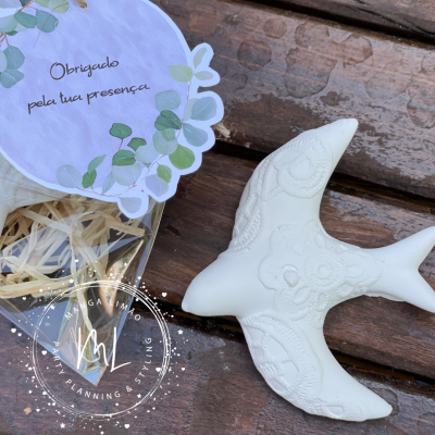 Pássaro decorativo branco com padrão em relevo ao lado de cartão de agradecimento com folhas verdes