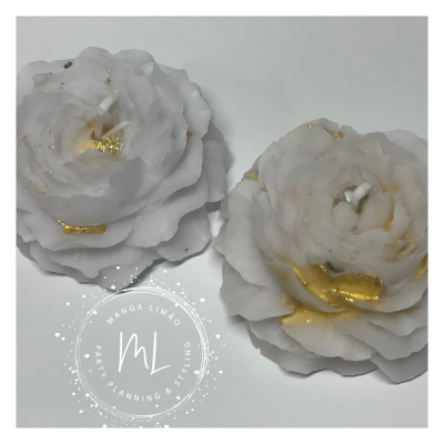 Duas velas flor branca com detalhes dourados sobre superfície branca com logotipo ML