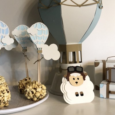 Decoração de festa com balões de ar quente em madeira e papel azul e branco e ovelha em papel-cartão.