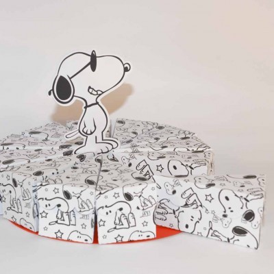 Doces embalados com estampas Snoopy organizados como fatias de bolo com figura de Snoopy grande em cartão