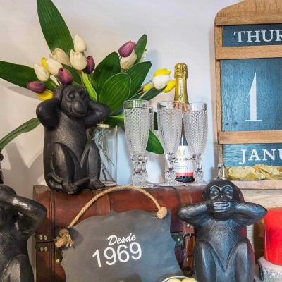 Estátuas de macacos, tulipas, garrafas, bolo vermelho e calendário de madeira azul indicando quinta-feira 10 de janeiro.